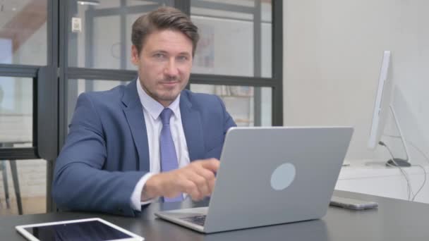 Reifer erwachsener Geschäftsmann zeigt auf Kamera im Büro - Filmmaterial, Video