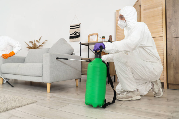 Mannelijke werknemer desinfecterende bank in de kamer - Foto, afbeelding