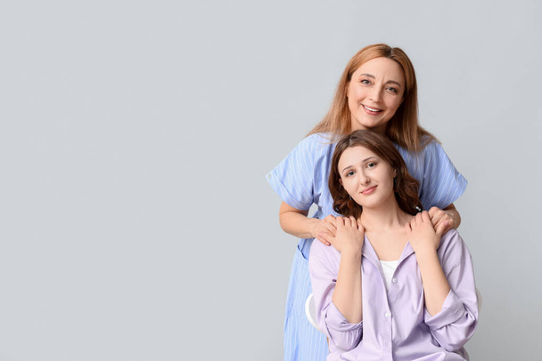 Kaunis kypsä nainen tyttärensä kanssa harmaalla taustalla. Äitienpäivän juhla - Valokuva, kuva