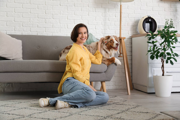 Bella giovane donna con simpatico cane pastore australiano sul divano in cucina - Foto, immagini