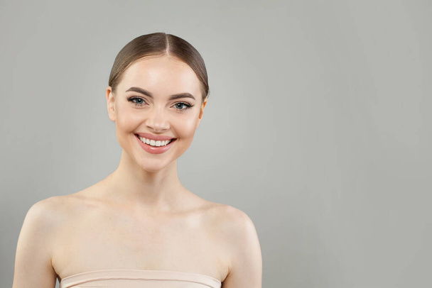 Vrolijke gezonde model vrouw met mooie huid en schattige glimlach op witte achtergrond, studio portret. Gezichtsbehandeling, huidverzorging en kosmetologie - Foto, afbeelding