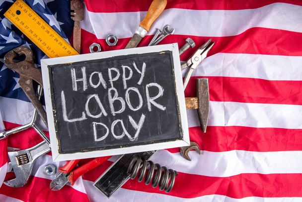 Amerikan Ulusal Vatansever İşçiler Mutlu İşçi Bayramı tatili geçmişi. Ahşap zemin üzerinde yıldızlı inşaat ve imalat araçları, kırmızı beyaz mavi çizgili Amerikan bayrağı - Fotoğraf, Görsel
