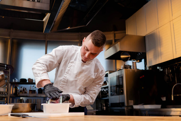 uno chef in cucina in una giacca bianca griglie barbabietole su un tavolo in un dollaro - Foto, immagini