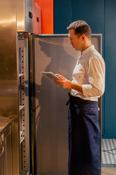 professzionális konyhafőnök belenéz a hűtőbe, és úgy dönt, hozzávalókat főzés élelmiszer koncepció - Fotó, kép