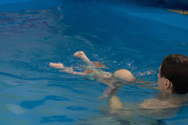 Úszó edző megtanít egy gyereket a víz alá merülésre. - Fotó, kép