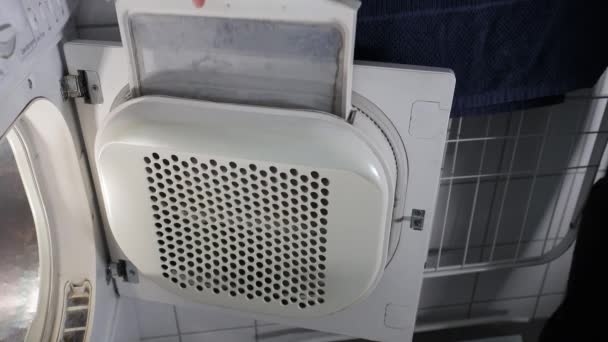 A man removes lint from an electric  clothes tumble dryer - Footage, Video