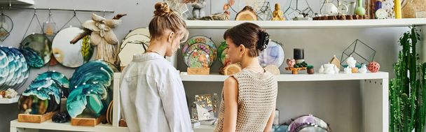Twee vrouwen, een liefdevol lesbisch paar, staan samen in een kunststudio, presenteren hun creativiteit. - Foto, afbeelding