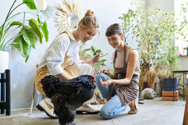 Coppia lesbica amorevolmente accarezzare un pollo in uno studio d'arte. - Foto, immagini