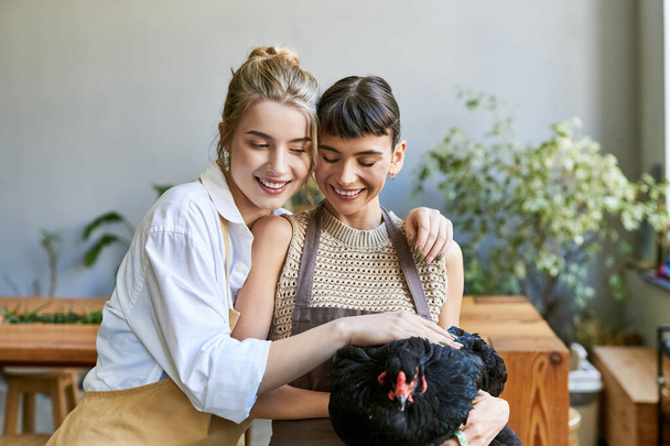 Deux femmes dans un studio d'art, l'une tenant tendrement un poulet noir. - Photo, image