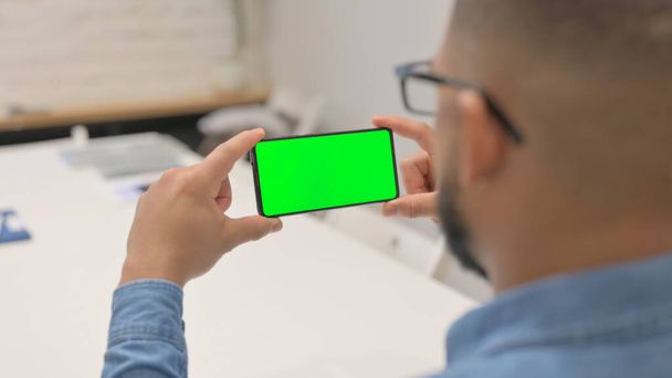 緑のスクリーンが付いている電話の横を握るアフリカ人男 - 写真・画像