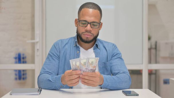 Junger Mann mit gemischter Rasse beim Geldzählen - Foto, Bild