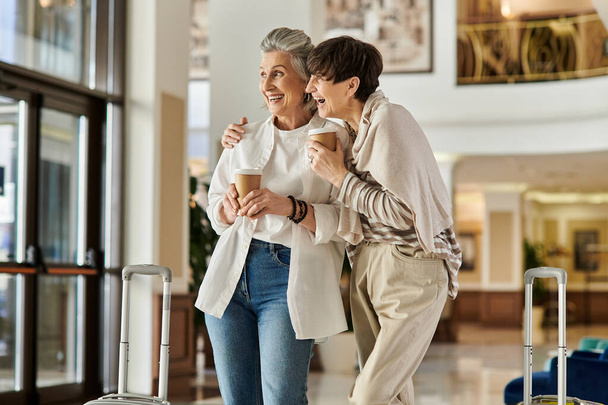 Ηλικιωμένο ζευγάρι λεσβιών μοιράζονται μια τρυφερή στιγμή μαζί σε ένα ξενοδοχείο. - Φωτογραφία, εικόνα