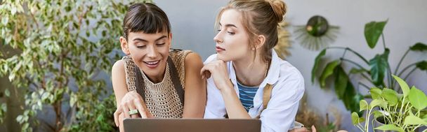 Дві молоді жінки, занурені в сяйво екрану ноутбука в художній студії. - Фото, зображення