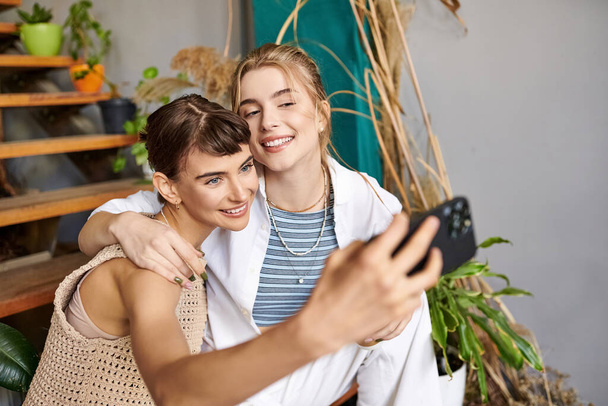 Uma mulher capturando uma selfie com seu amigo em um estúdio de arte. - Foto, Imagem