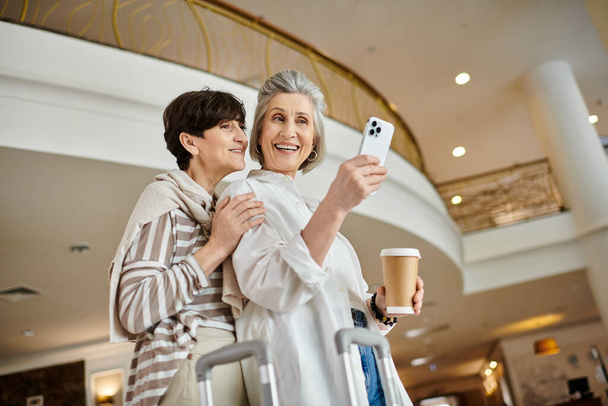 Egy nő mosolyog, miközben szelfit csinál a mobiljával a társa mellett.. - Fotó, kép