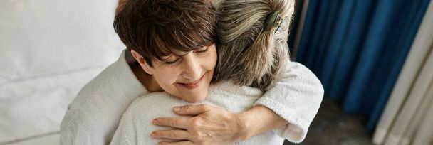 Ältere lesbische Paar zärtlich umarmt eine Katze in einem gemütlichen Moment. - Foto, Bild