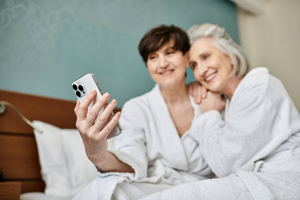 Пожилые женщины запечатлели момент с помощью мобильного телефона. - Фото, изображение