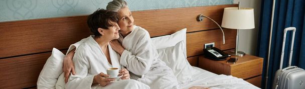 愛するシニアレズビアンカップルは,ベッドの上に座って平和な瞬間を楽しんでいます. - 写真・画像