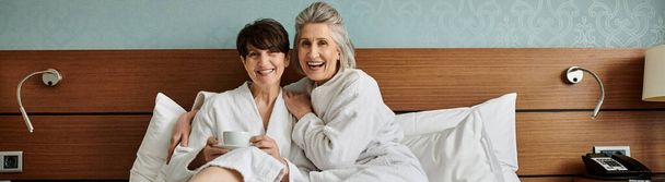 Ein zärtlicher Moment zwischen einem liebenden älteren lesbischen Paar, als sie zusammen im Bett liegen. - Foto, Bild