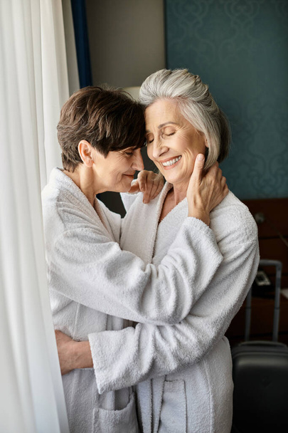 Tender moment as older woman embraces her partner in hotel. - Photo, Image