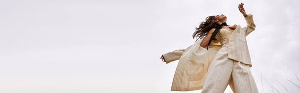 Una joven con un traje blanco que vuela con gracia por el aire, disfrutando de la brisa del verano en un entorno natural. - Foto, imagen