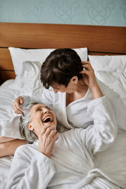 Τρυφερή αγάπη μεταξύ ηλικιωμένων λεσβιών ζευγαριών στο κρεβάτι. - Φωτογραφία, εικόνα