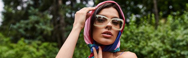 Eine schöne junge Frau mit einem Schal um den Kopf, die eine Sommerbrise in der Natur genießt. - Foto, Bild