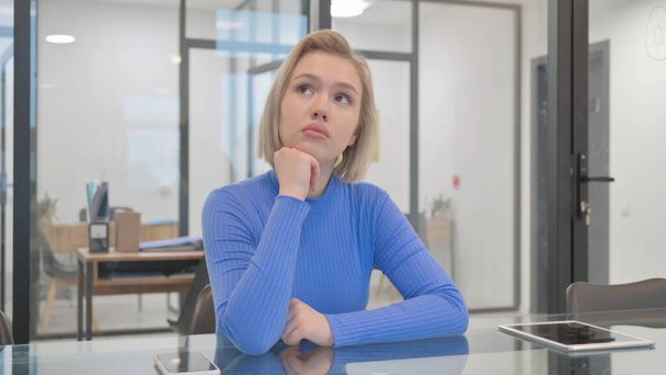 Pensive mladá žena sedí v kanceláři - Fotografie, Obrázek