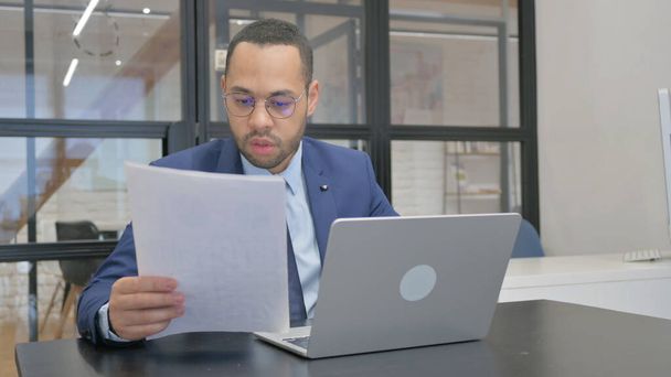 Mann im Anzug arbeitet an Dokumenten und Laptop - Foto, Bild
