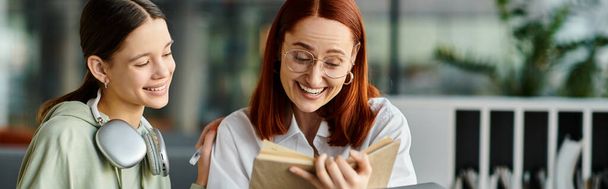 Un tuteur, une rousse, transmet des connaissances à son adolescent, tous deux absorbés dans un livre au milieu d'un cadre d'apprentissage moderne. - Photo, image