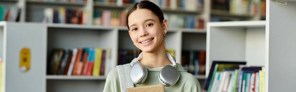 uma adolescente com um livro em um ambiente de biblioteca, educação moderna. - Foto, Imagem