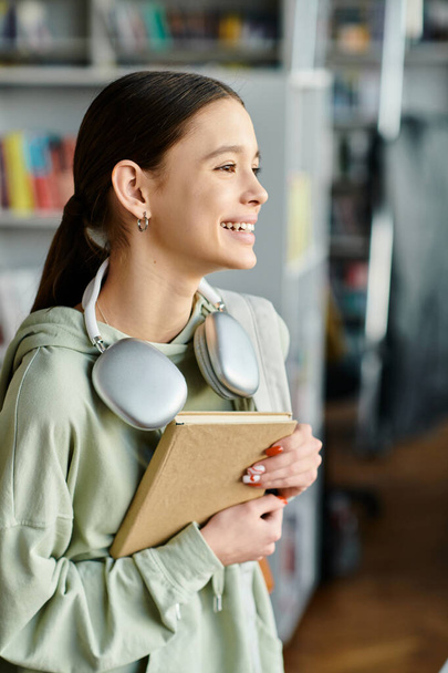 meisje het dragen van een koptelefoon houdt een boek tijdens het aangaan van een naschoolse les - Foto, afbeelding