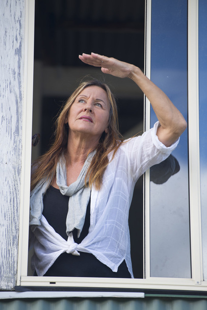 Woman with hand up watching from window - Zdjęcie, obraz
