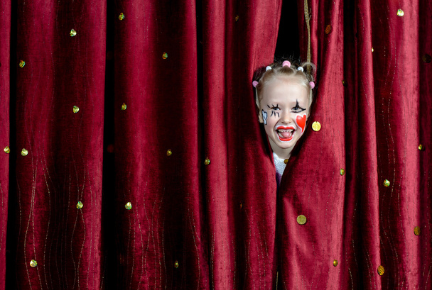 Chica usando payaso maquillaje mirando a través de cortinas
 - Foto, imagen