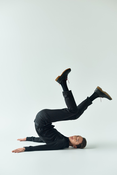 A young queer person showcases her strength and balance as she performs a handstand on a white background. - Photo, Image