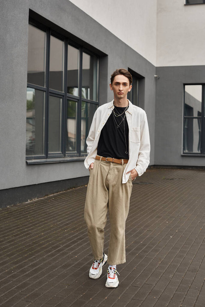 Молода квір-людина впевнено стоїть в стильному вбранні перед будівлею, породжуючи гордість і впевненість. - Фото, зображення