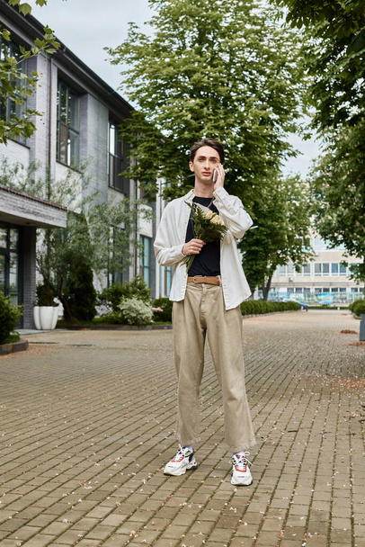 Eine junge queere Person in stilvoller Kleidung mit einem lebendigen Blumenstrauß vor einem Gebäude. - Foto, Bild