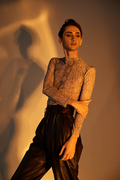 Uma jovem queer pessoa confiantemente balança calças de couro, uma roupa elegante e capacitante. - Foto, Imagem