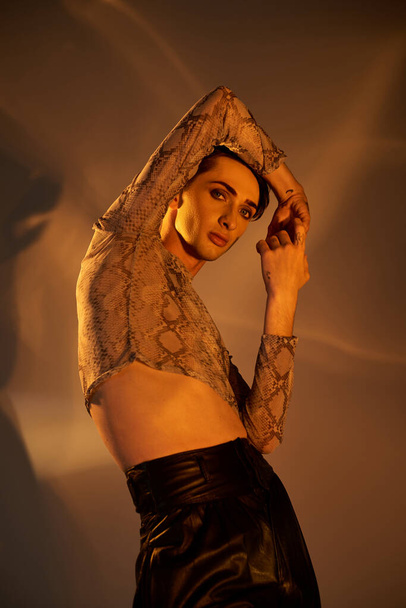Ένα νεαρό queer άτομο με αυτοπεποίθηση θέτει σε μια δερμάτινη φούστα, αποπνέοντας κομψότητα και υπερηφάνεια στην κομψή ενδυμασία της. - Φωτογραφία, εικόνα