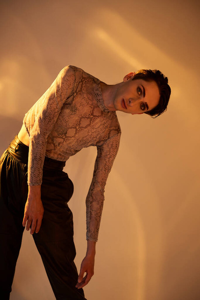 A young queer man with a tattooed body strikes a bold pose against a white background. - Photo, Image