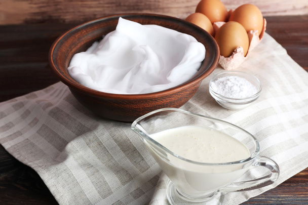 Whipped egg whites and other ingredients for cream on wooden table, closeup - Фото, зображення