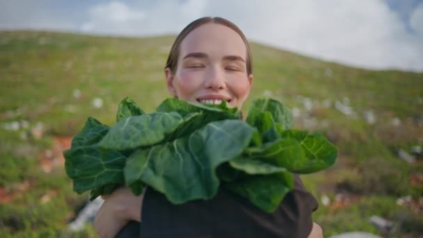 野菜をフィールドクローズアップに保持している女性. ハッピーな女の子は収穫を楽しんでいるキャベツとポーズします. 緑色の新鮮なケールと笑顔の庭師は有機農地の収穫を示しています. ビーガン健康的な栄養コンセプト - 映像、動画