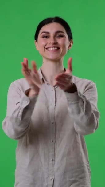 Πορτρέτο μιας χαμογελαστής και χαρούμενης Καυκάσιας που χειροκροτεί στο πράσινο φόντο. Συγχαρητήρια, εορταστική ιδέα. Κάθετη βίντεο. - Πλάνα, βίντεο