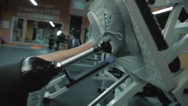 Sledování záběru motivovaného sportovce s protetickým tréninkem na stroji na lisování nohou v moderní tělocvičně. Dospělý sportovní muž s umělou končetinou dělá sílu cvičení pomocí profesionálního sportovního vybavení. - Záběry, video