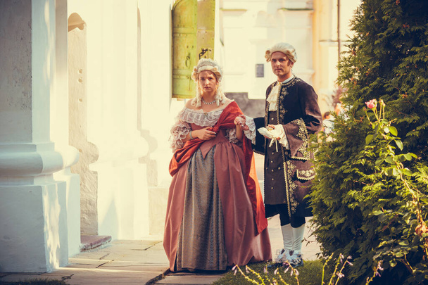 Portret van blonde vrouw en man gekleed in historische barokke kleren met ouderwetse kapsel, buiten. Luxe middeleeuwse jurk. Retro stijl en historische kleding concepten - Foto, afbeelding