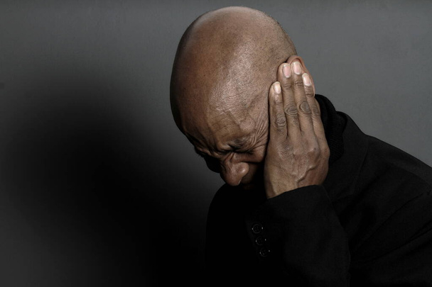 Homme souffrant de surdité et de perte auditive fermeture des oreilles avec les mains sur fond sombre - Photo, image