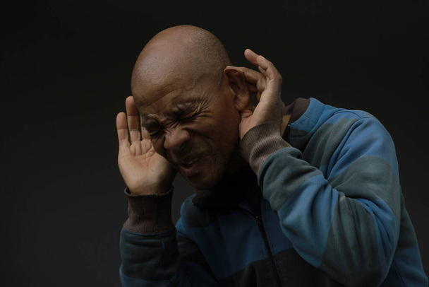 Afrikai amerikai férfi szenved süketség és hallásvesztés fogja a kezét a fülét a sötét háttér - Fotó, kép