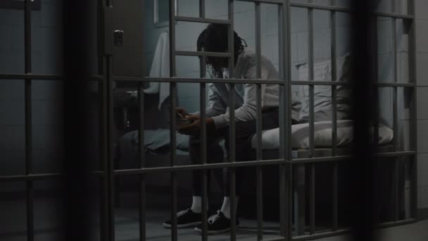 Az afro-amerikai fiatal rab undorító börtönkaját eszik vastálból, az ágyon ülve a börtöncellában. Tinédzser bűnöző, a rab börtönben tölti a börtönbüntetését. Ifjúsági fogolytábor. - Felvétel, videó
