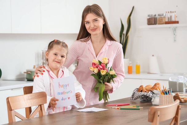 Linda hija saludando a su mamá con el Día de las Madres con ramo de tulipanes en la cocina - Foto, imagen