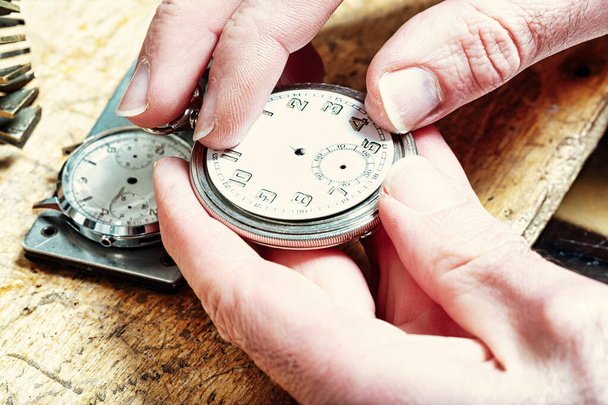 le dita dell'artigiano regolano i piccoli meccanismi all'interno dell'orologio, l'essenza della puntualità in corso - Foto, immagini